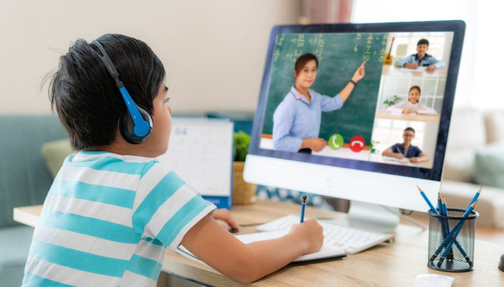 Asian boy student video conference e-learning with teacher and classmates on computer in living room at home. Homeschooling and distance learning, online, education, and internet.