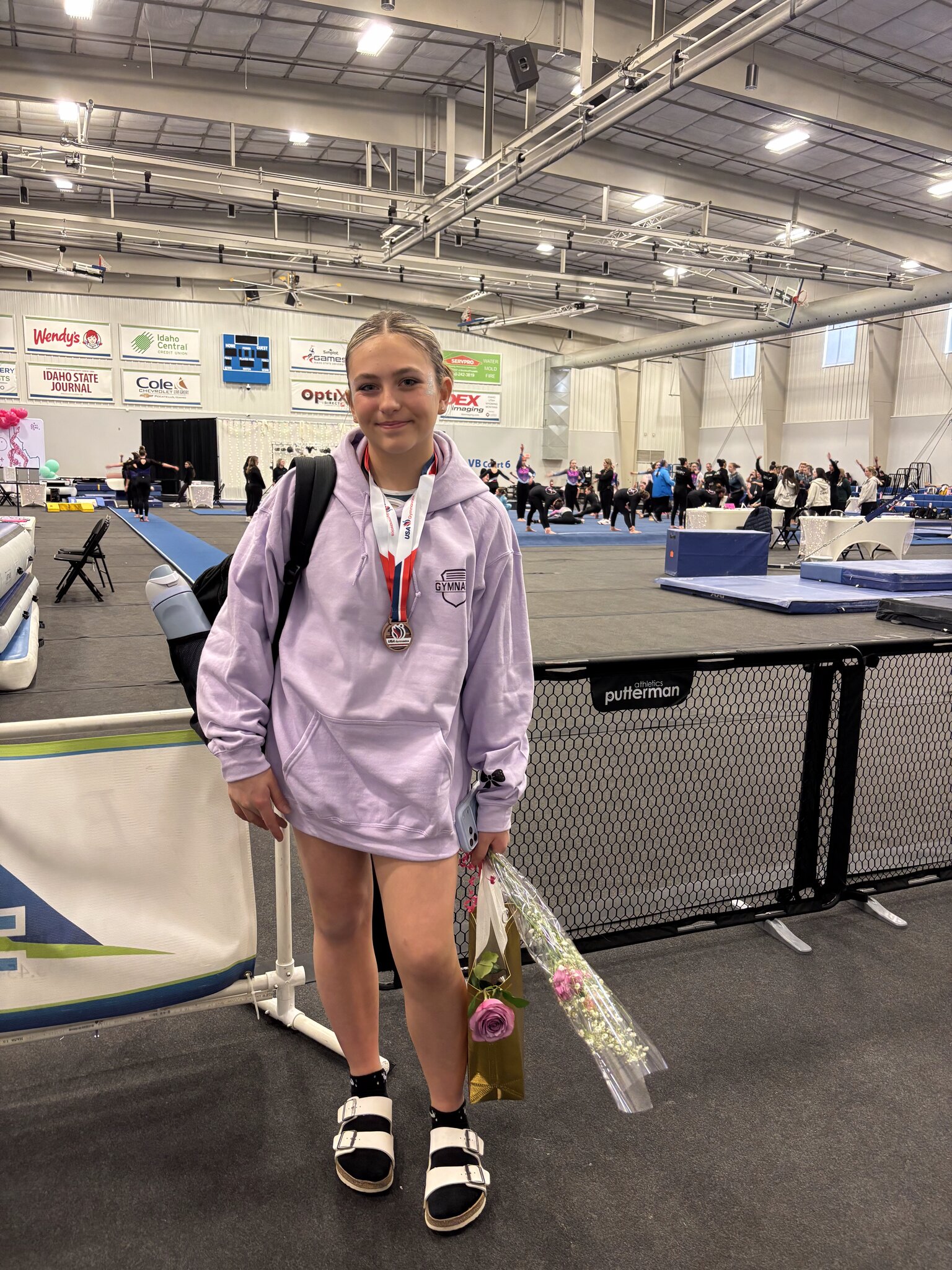 Kaitlin at a gymnastics meet wearing a medal after returning to the sport following knee surgery