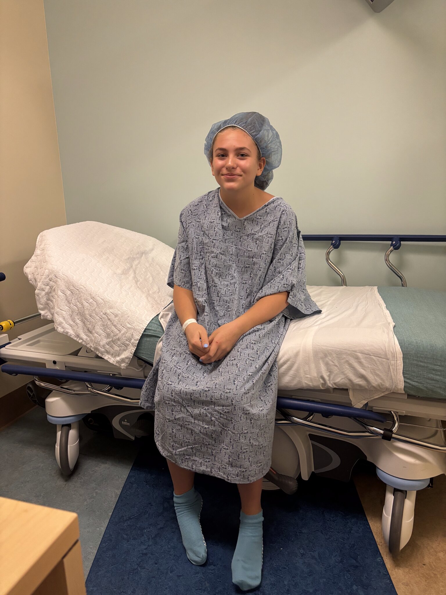 Kaitlin in a hospital gown before her knee surgery at Rady Children's Hospital
