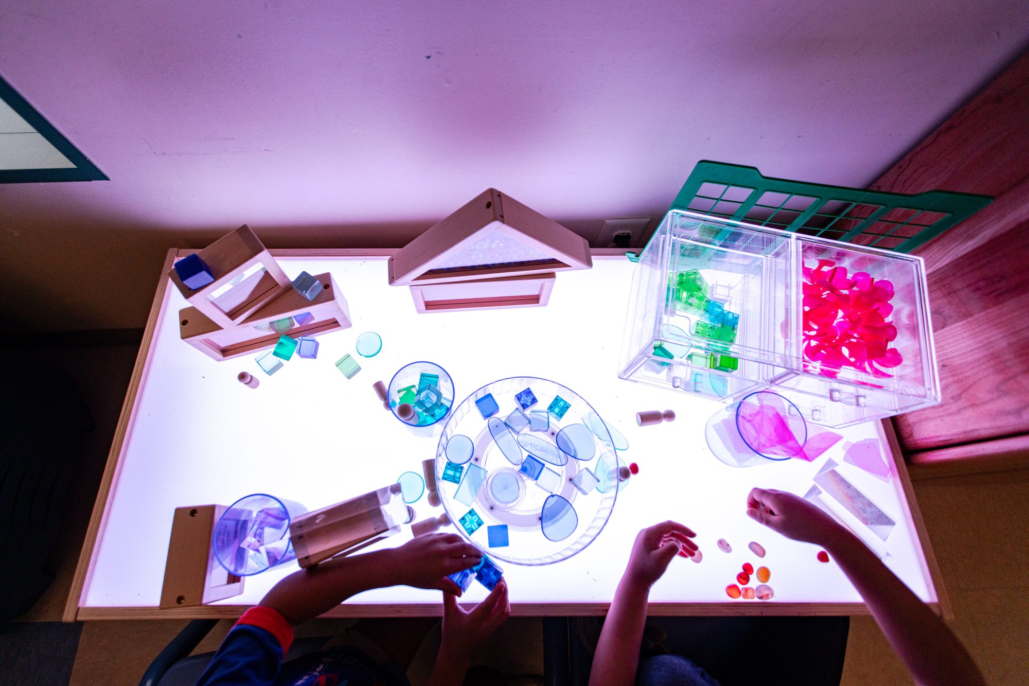 Child exploring translucent blocks on a light table at Alexa's PLAYC