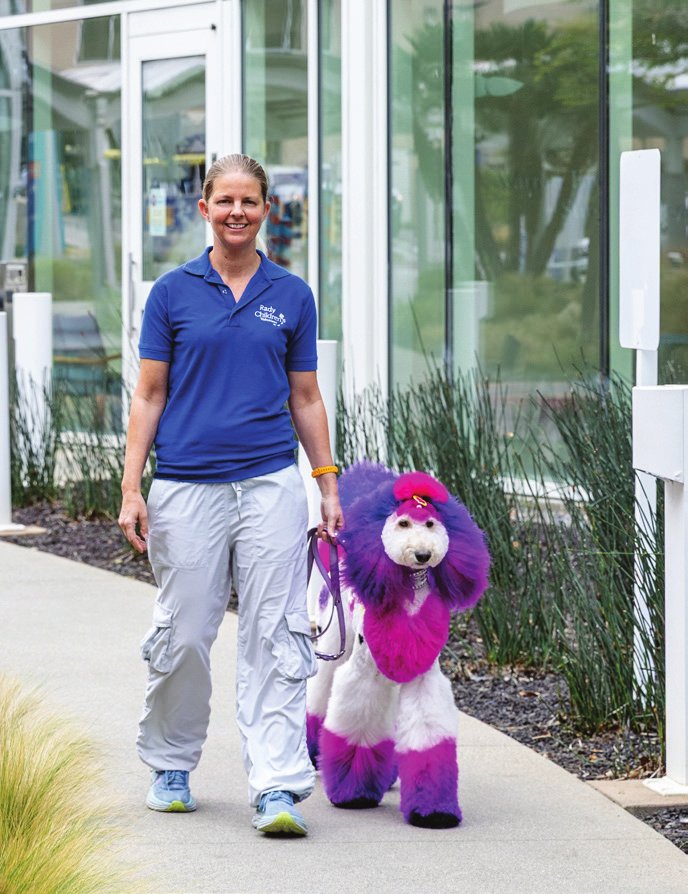 Volunteer Angela Schoonover walking Zoe the therapy dog outside Rady Children's